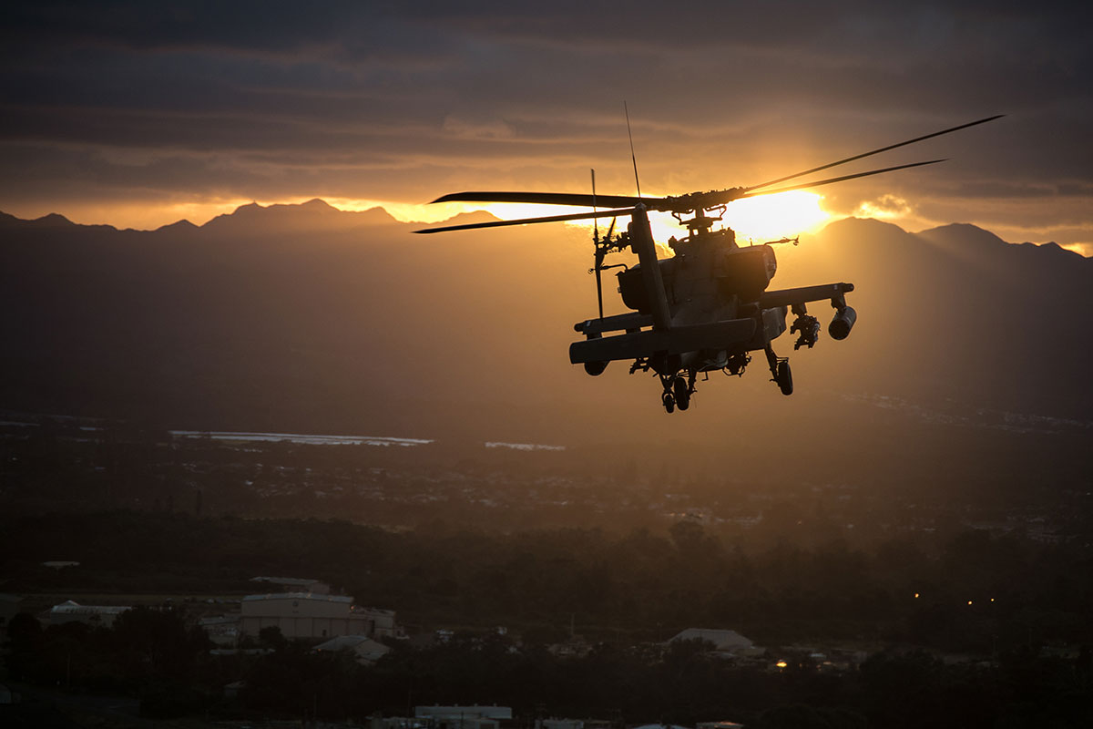 apache helicopter flying at sunset