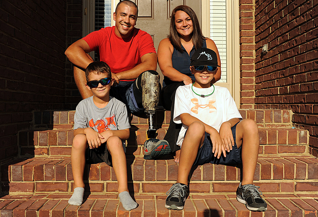 Family of 4 sitting on the steps outside of their house