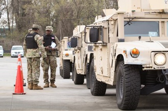 National guard personnel standing by military vehicles