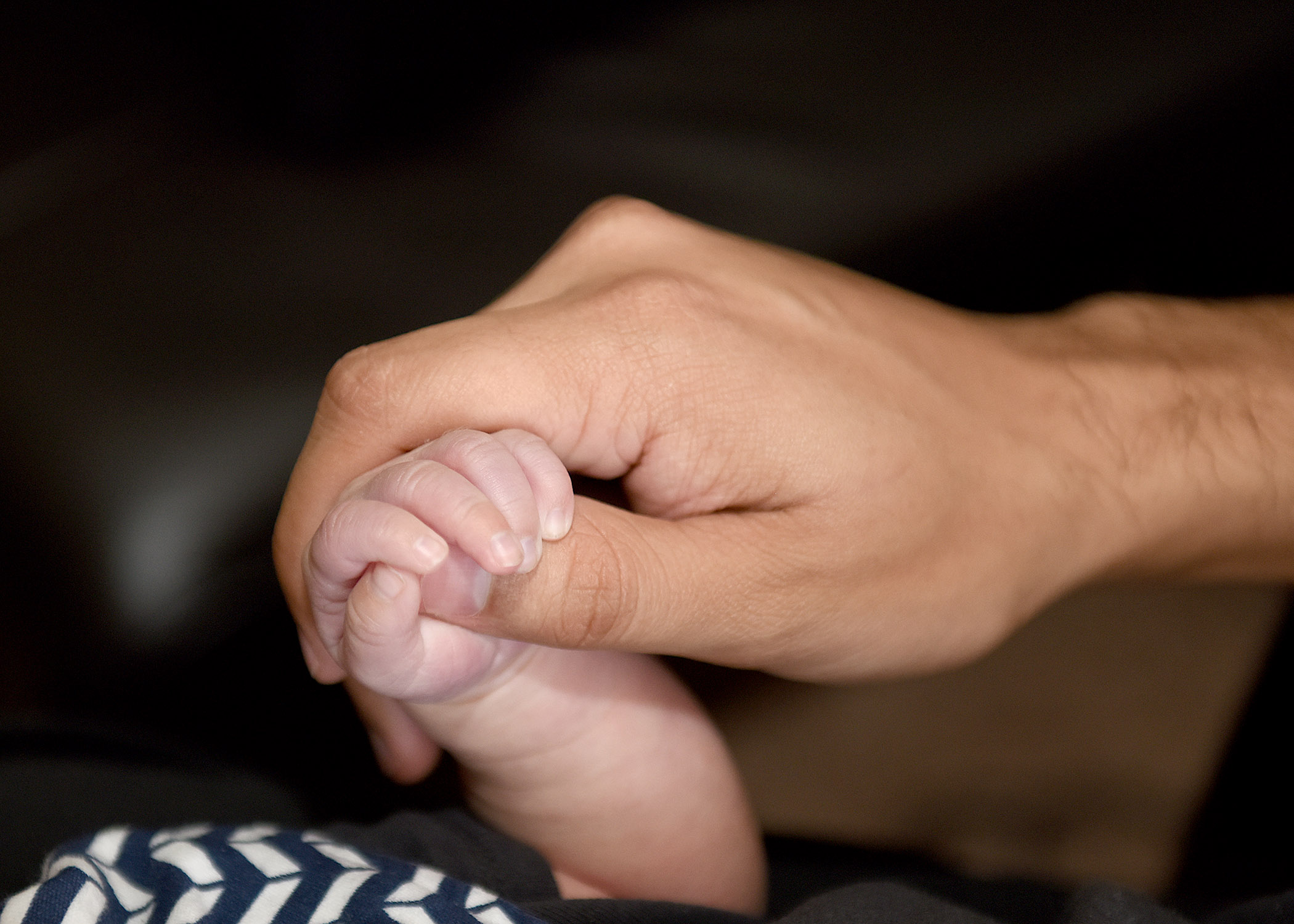 Infant holding parent's hand