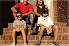 Family of 4 sitting on the steps outside of their house