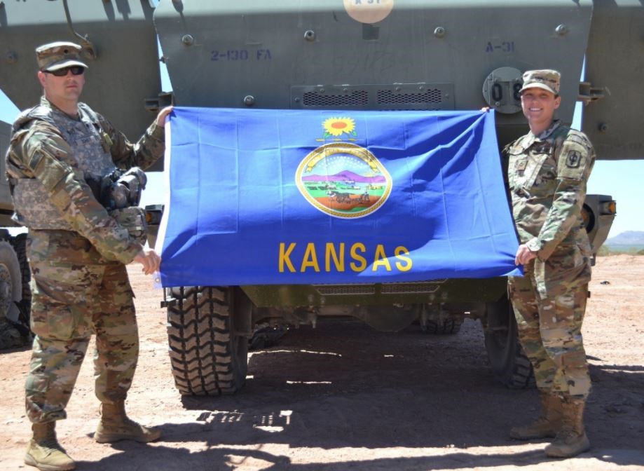 two servicemen holding the Kansas flag