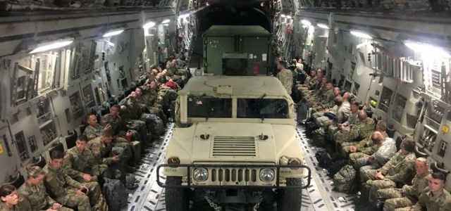 soliders and a humvee flying in a plane