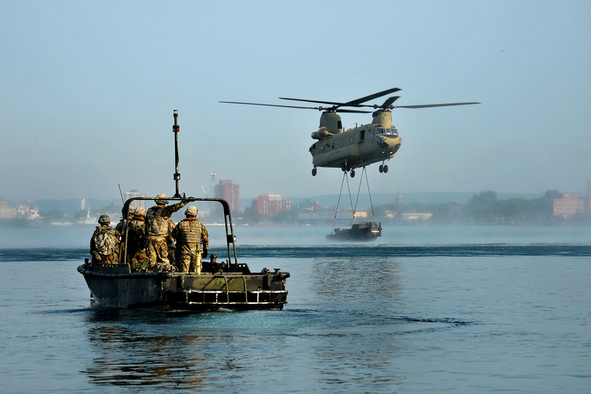 chinook helicopter lowering a boat in the water