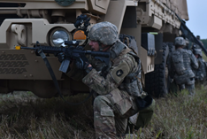 soliders kneeling behind a military vehicle