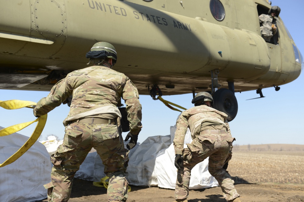 Soldiers hooking up cargo to a chinook 