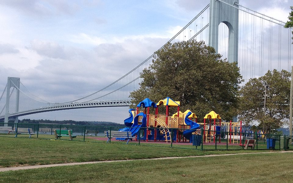 kids playing on a playgroud with a suspenion bridge in the background